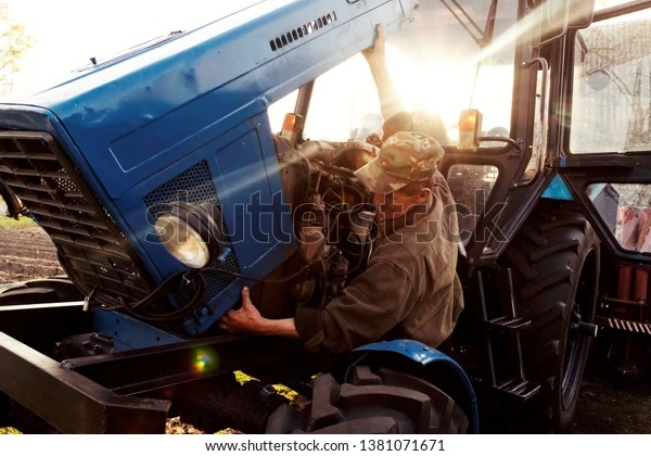 farmer-mechanic-repairing-blue-tractor-600w-1381071671